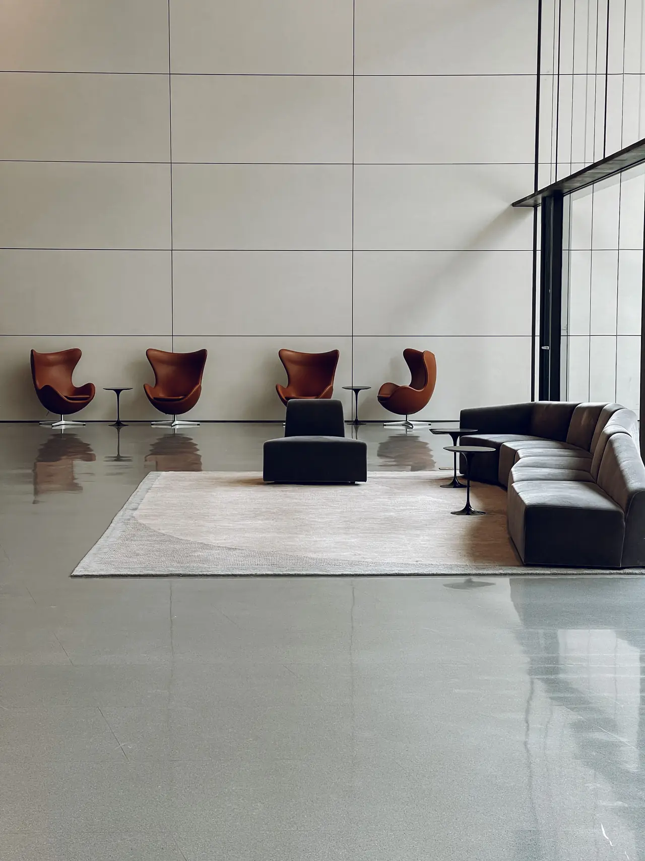 Hall d'accueil au sol poli, fauteuils design alignés et canapé